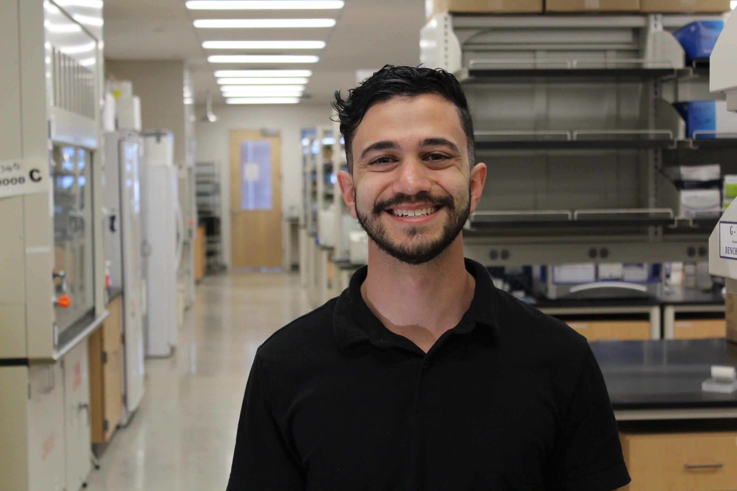 Amir Alayoubi smiling at the camera while standing the CSU Biology lab.